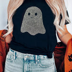 A woman wearing a black t-shirt with a glittery ghost graphic on the front, paired with light-wash denim jeans.