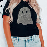 A woman wearing a black short-sleeve t-shirt with a glittery ghost graphic on the front, paired with light-wash blue jeans.