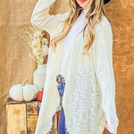 Woman wearing a white scarf and blue hat against a wooden background with decorative items.